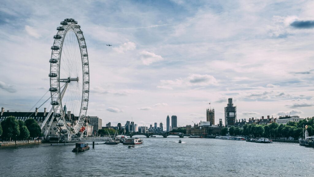 Scenic view of the London Eye on the River Thames with clear blue skies and city skyline.